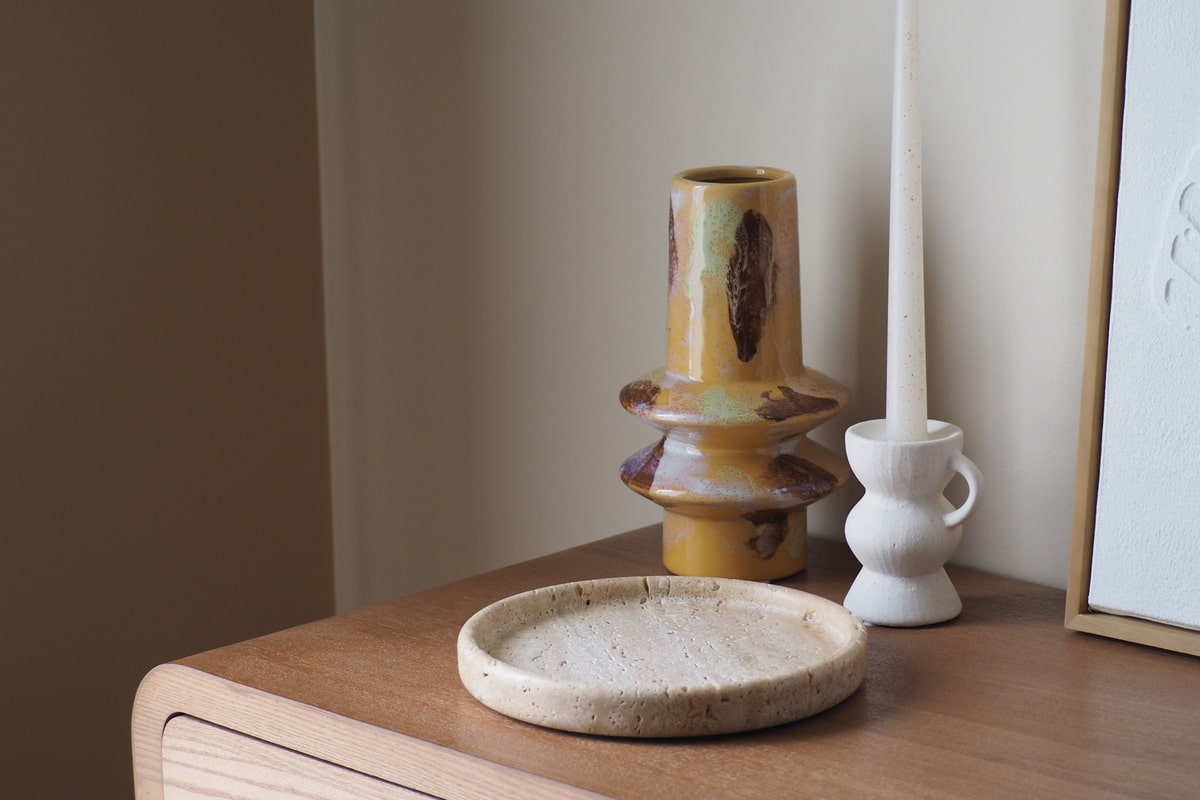 Sélection d'objets de décoration offerts en cadeau : vase en céramique, bougie parfumée et plaid posés sur une table basse en bois